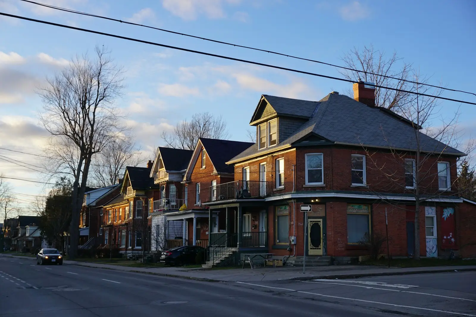 A row of brick houses along a street corner in Kingston, Ontario, lit by low evening sun