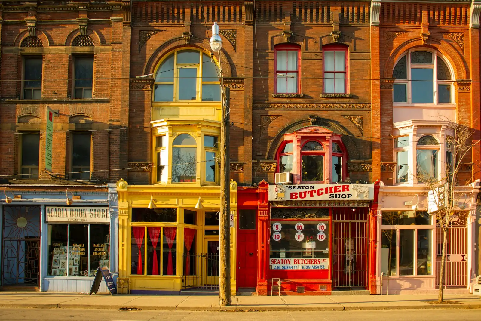 Independent shops on the ground floor of a red-brick Victorian building on a Toronto street